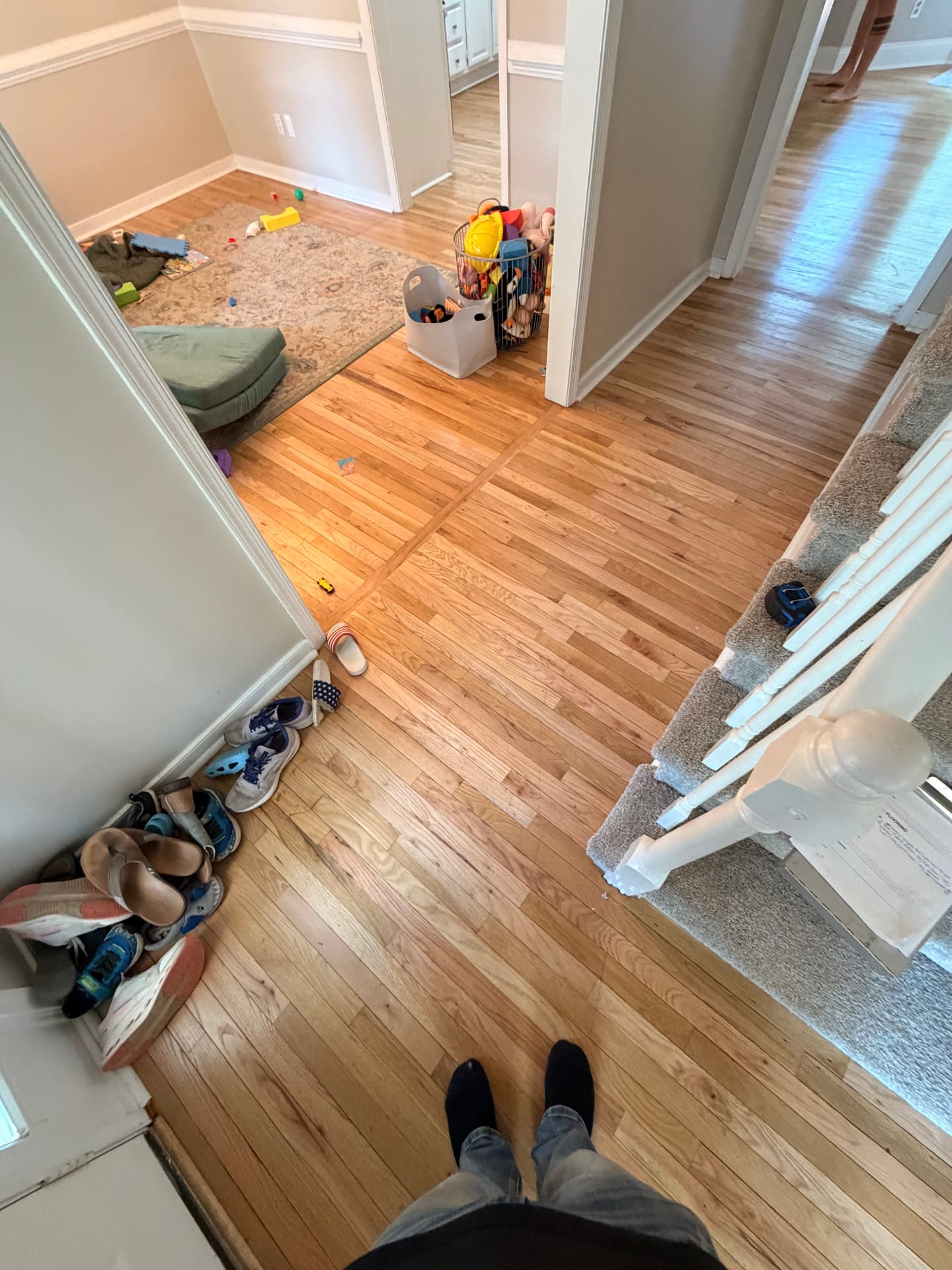 Existing hardwood flooring through a hallway and adjoining rooms before replacement