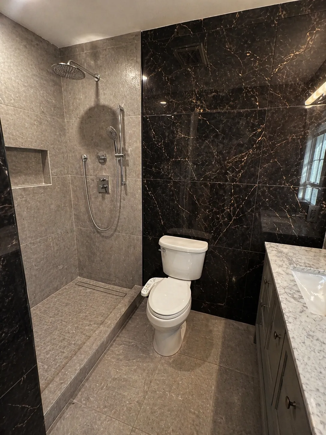 Fredericksburg VA bathroom remodel with dark marble feature wall, walk-in rain shower, and quartz vanity